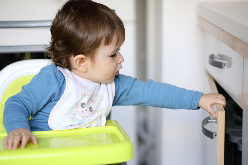 Toddler in high chair reached for unsecured kitchen cabinet.
