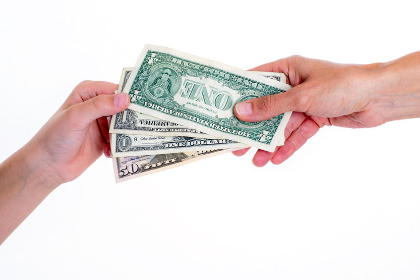 Child's hand and adult hand holding dollar bill.