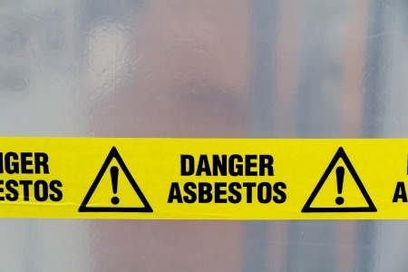 Yellow warning sign that says danger asbestos.
