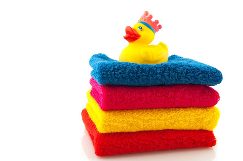 Four colorful stacked bath towels with rubber ducky on top.