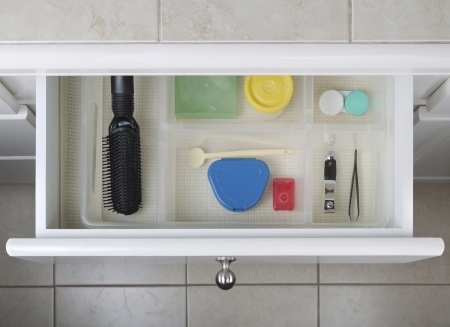 Organized bathroom drawer with brush, toiletries inside.