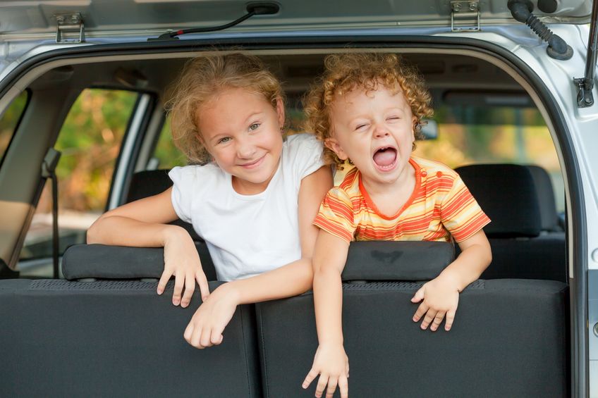 Two happy girls in minivan hatchback.