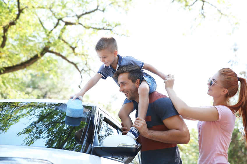Young boy on dad's shoulders washing car.