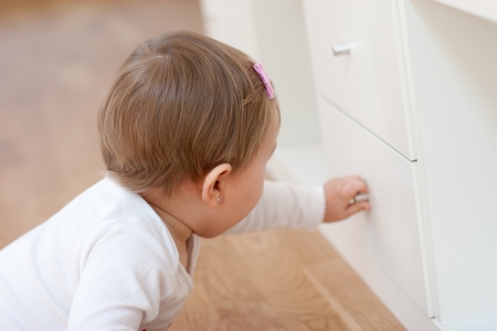 Baby with hand on kitchen drawer pull.