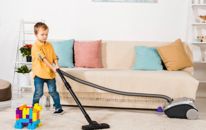 Young boy vacuuming living room.