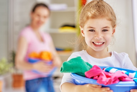 Young girl holding laundry in basket.