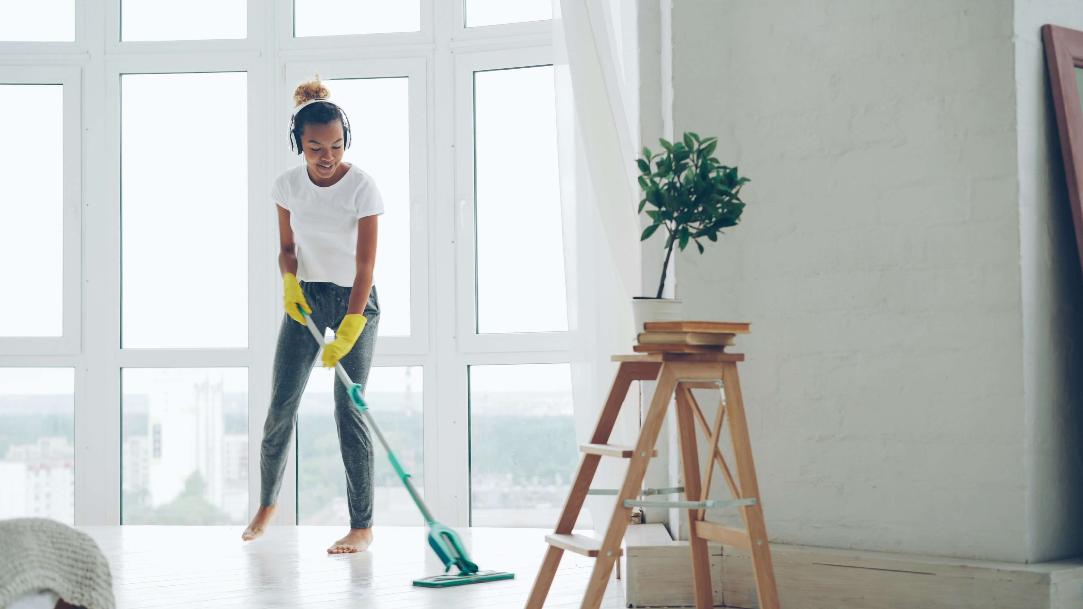 A teenager is mopping a wooden floor.