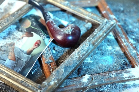 Smoking pipe and shattered picture frames on ground.