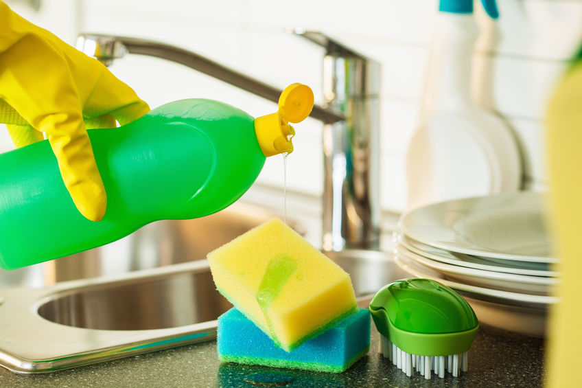 Washing kitchen sponges at sink.