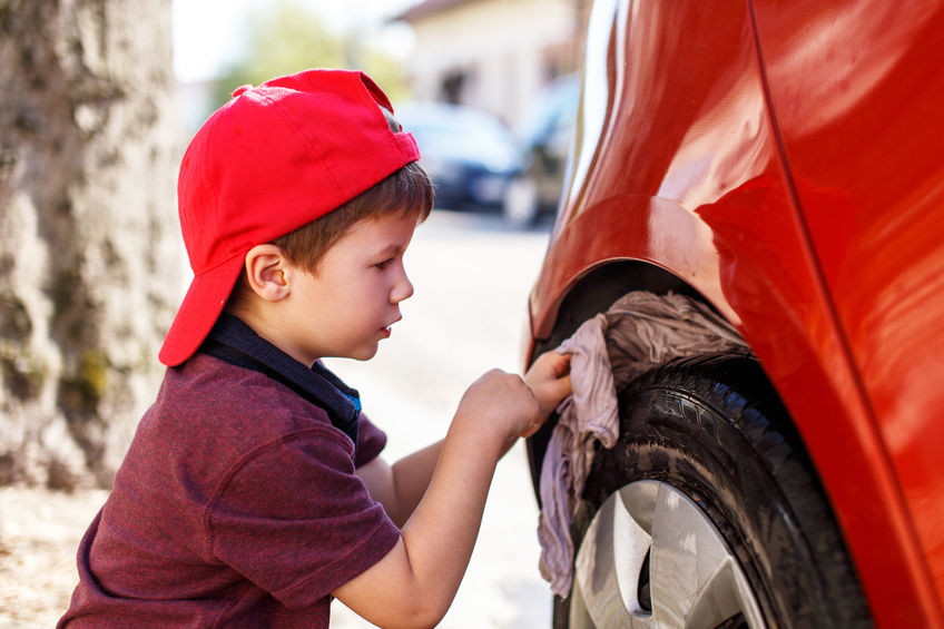 Young boy detailing car tire.