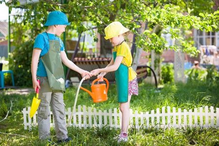 Boy and girl watering garden.
