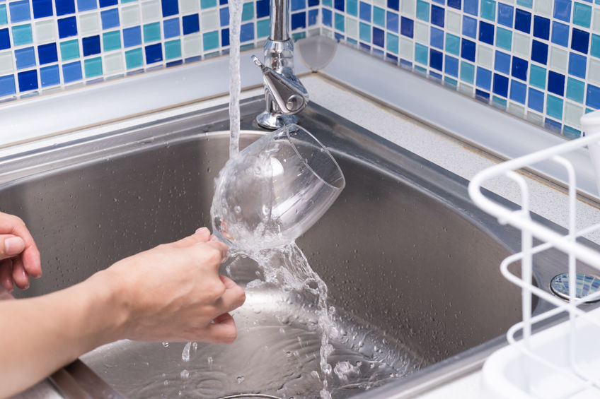A woman is washing a glass.