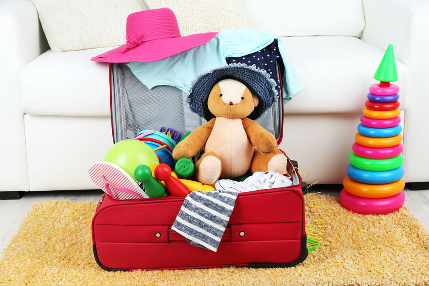 Suitcase on floor packed with children's items and toys.