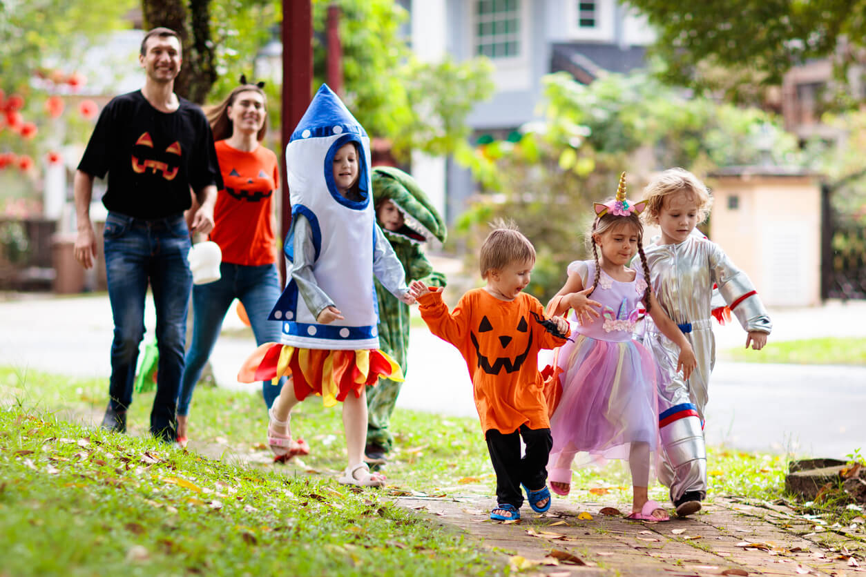 Family in Halloween costumes walking on street.