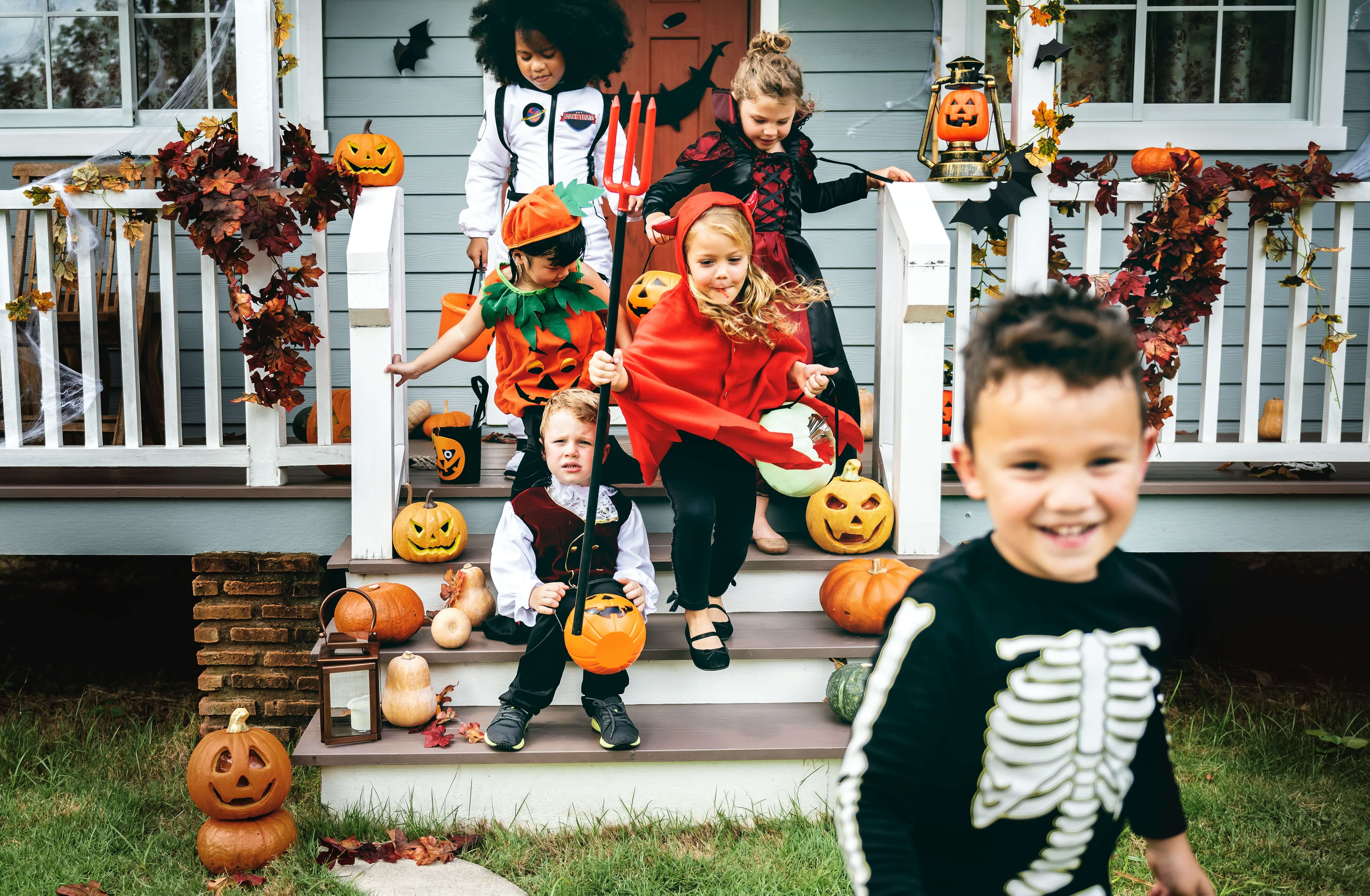 Children in costume in front of a Halloween-themed house.