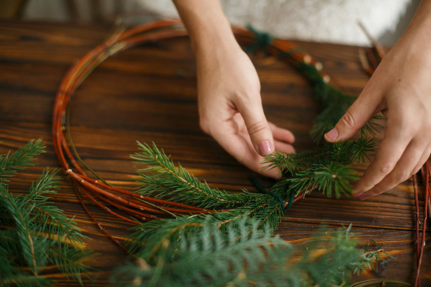 Arranging holiday greenery on table.