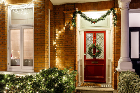 Front door of brick home decorated with holiday wreath and decor.