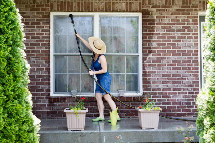 Woman washing exterior windows of home.