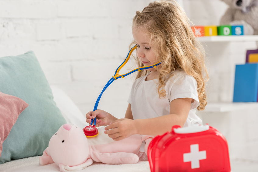 Young girl with stethoscope checking teddy bear's heart rate.