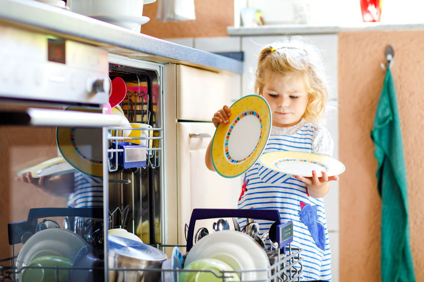 Young girl loading dishes into dishwasher.