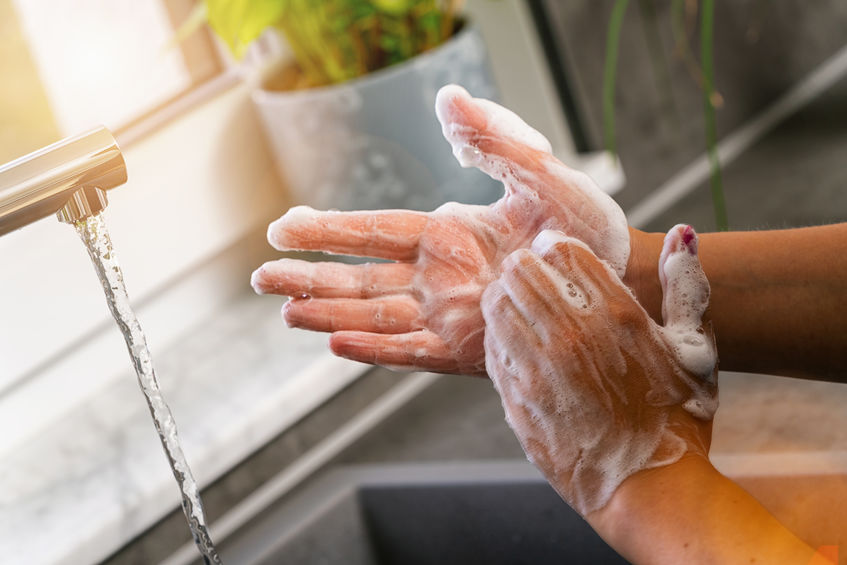 Washing soapy hands under running water.