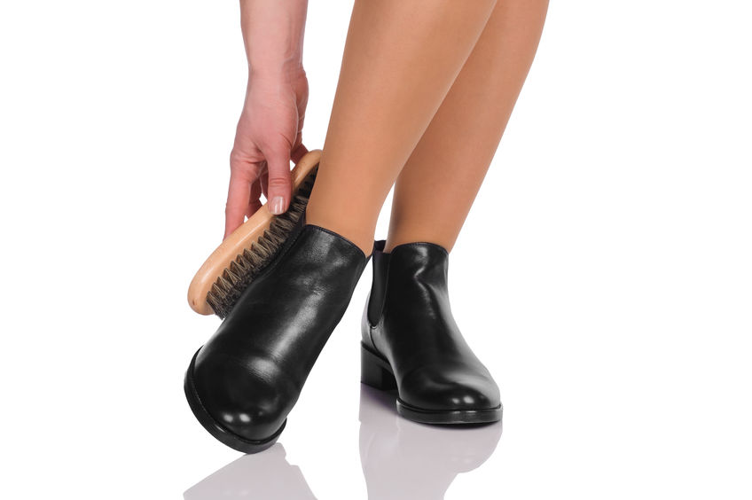 Woman brushing black leather ankle boots.