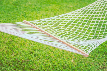 White cotton mesh hammock hanging outdoors.