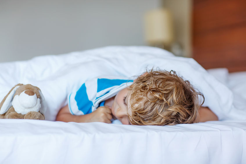Young boy asleep on bed.
