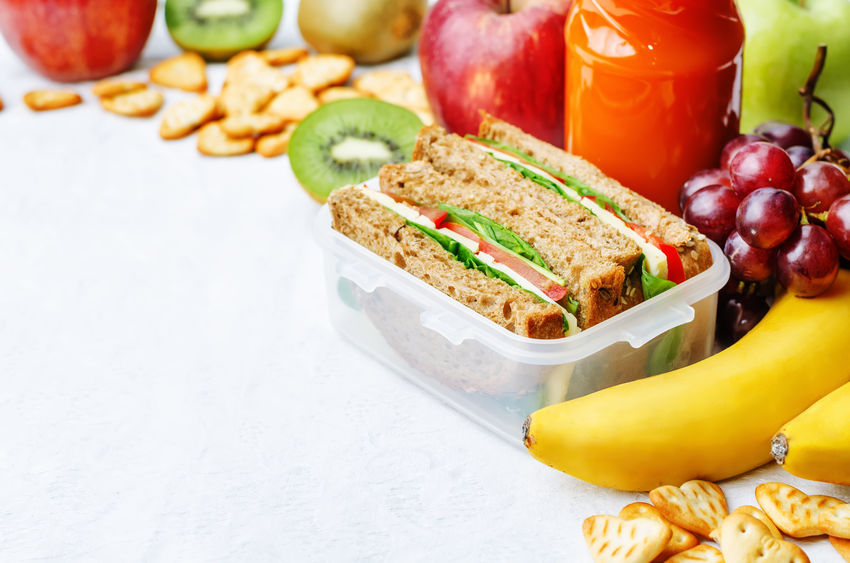 Sandwich in container and fresh fruit.