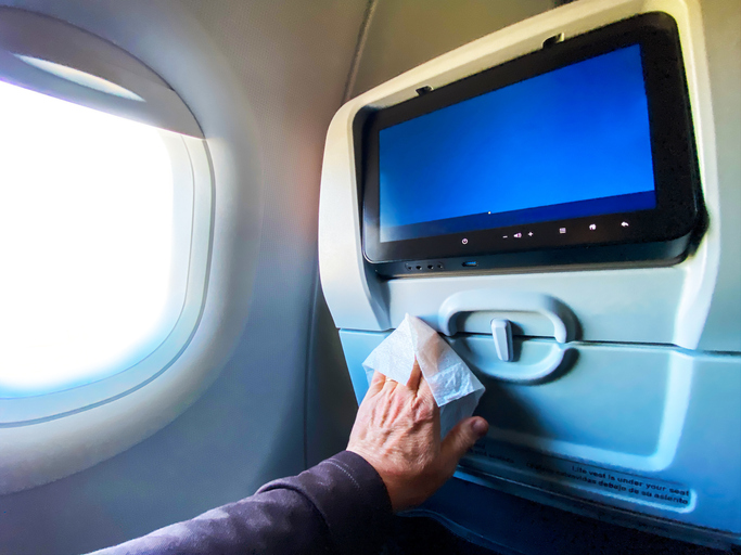 Hand wiping clean an airplane tray table.