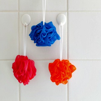 Shower scrubbers hanging on bathroom wall hooks.