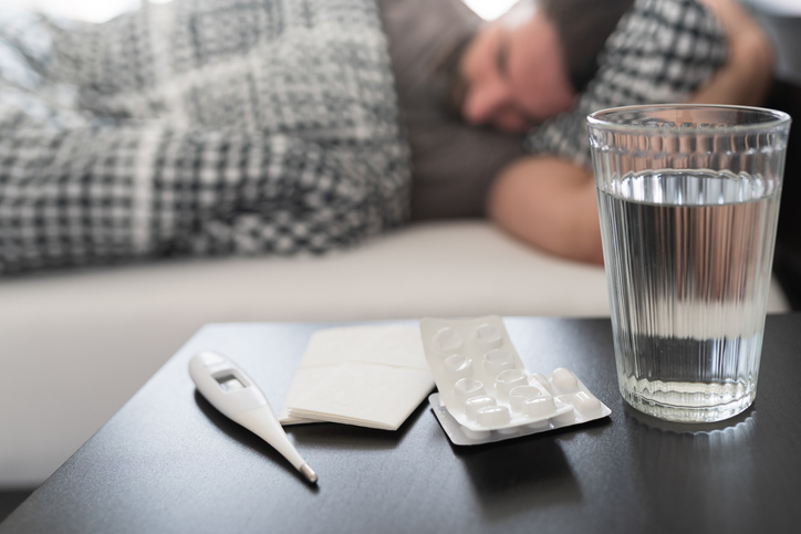Man in bed with side table with medicines.