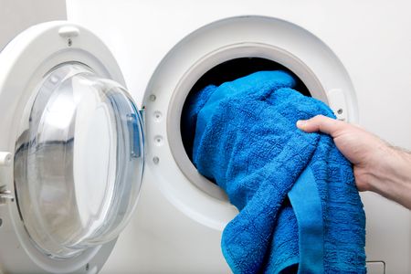 Woman taking blue towel from dryer.