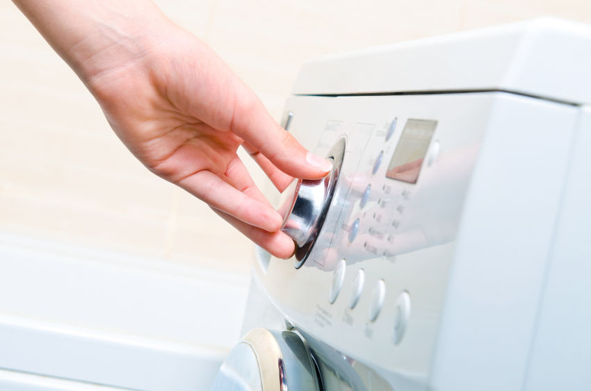 Woman's hand setting washing machine.