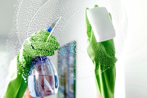 Gloved hands cleaning window.